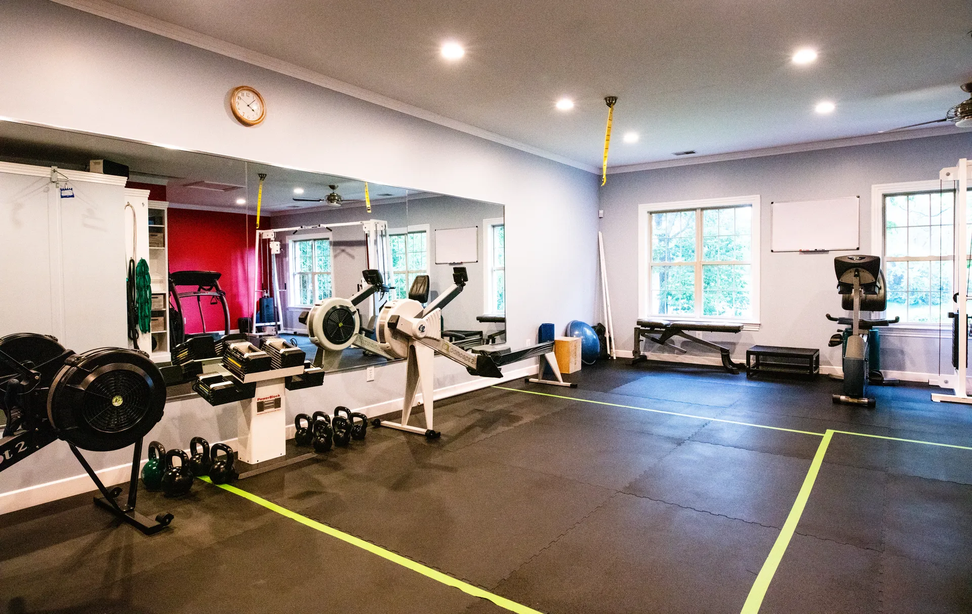The St. Matthews training floor: mirrored wall, rowers, a plate-loaded rack and bikes, windows down one side.