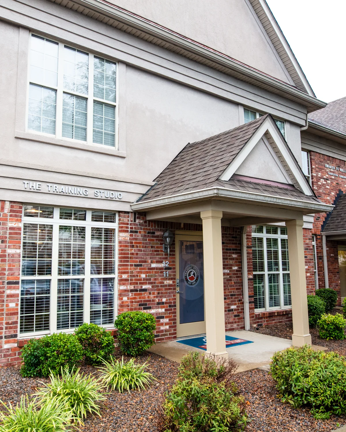 The St. Matthews studio: a brick-and-stucco townhouse-style unit with a covered porch and The Training Studio sign over the door.